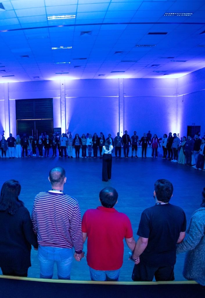 Grupo em dinâmica coletiva com iluminação azul e circular